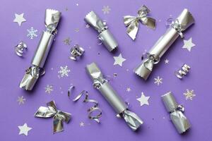 Christmas crackers with shiny confetti on color background, top view, copy space photo