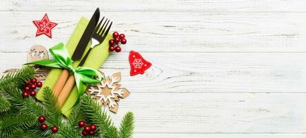 Top view of christmas decorations on wooden background. Fork and knife on napkin tied up with ribbon and empty space for your design. New year pattern concept photo