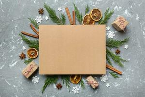 Flat lay Christmas composition. square Paper blank, pine tree branches, christmas decorations on Colored background. Top view, copy space for text photo