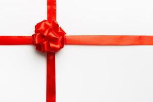 Top view of Red ribbon rolled and red bow isolated on colored background. Flat lay with copy space photo