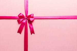 Top view of purple ribbon rolled and pink bow isolated on colored background. Flat lay with copy space photo