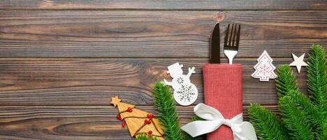 Top view Banner of fork and knife on napkin with christmas decorations and new year tree on wooden background. Holiday and festive concept with copy space photo