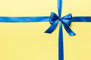 Top view of blue ribbon rolled and blue bow isolated on colored background. Flat lay with copy space photo