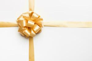 Top view of gold ribbon rolled and yellowbow isolated on colored background. Flat lay with copy space photo