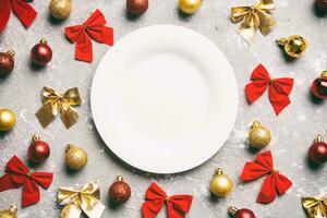 Top view of holiday dinner on cement background. Plate, baubles and bows. Christmas Eve concept photo