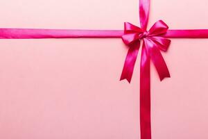 Top view of purple ribbon rolled and pink bow isolated on colored background. Flat lay with copy space photo