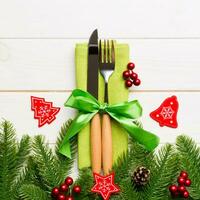 Top view of christmas decorations on wooden background. Fork and knife on napkin tied up with ribbon and empty space for your design. New year pattern concept photo