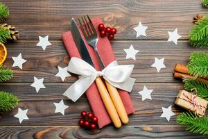 Top view of utensils on festive napkin on wooden background. Christmas decorations with dried fruits and cinnamon. Close up of New year dinner concept photo