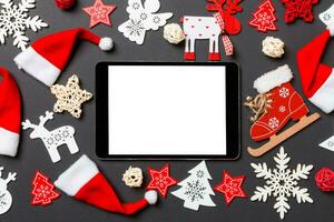 vista superior de la tableta digital. decoraciones de año nuevo sobre fondo negro. concepto de feliz navidad foto
