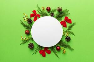 Flat lay Christmas composition. Round Paper blank, pine tree branches, christmas decorations on Colored background. Top view, copy space for text photo