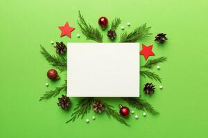Flat lay Christmas composition. square Paper blank, pine tree branches, christmas decorations on Colored background. Top view, copy space for text photo