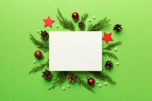 Flat lay Christmas composition. square Paper blank, pine tree branches, christmas decorations on Colored background. Top view, copy space for text photo