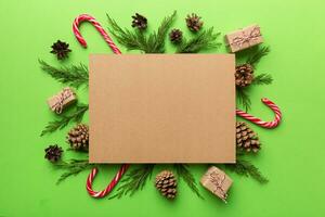 Flat lay Christmas composition. square Paper blank, pine tree branches, christmas decorations on Colored background. Top view, copy space for text photo