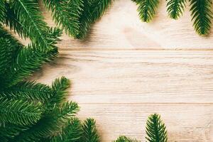 Top view of frame made of fir tree branches on wooden background. Christmas concept with empty space for your design photo