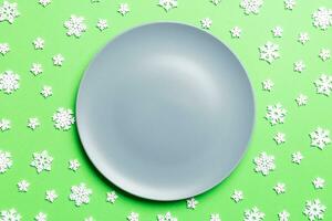 Top view of empty plate surrounded with snowflakes on colorful background. New Year dinner concept photo