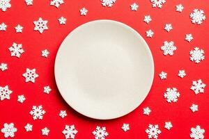 Top view of empty plate surrounded with snowflakes on colorful background. New Year dinner concept photo
