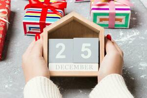 Top view of female hands holding a calendar on cement background. The twenty fifth of December. Holiday decorations. Christmas concept photo