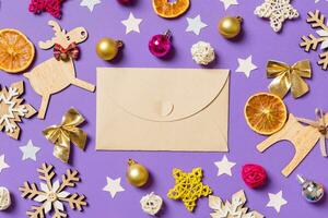 Top view of craft envelope surrounded with New Year toys and decorations on purple background. Christmas time concept photo
