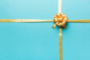 Top view of gold ribbon rolled and yellowbow isolated on colored background. Flat lay with copy space photo