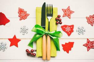 Top view of New Year dinner on wooden background. Festive cutlery on napkin with christmas decorations and toys. Close up of family holiday concept photo