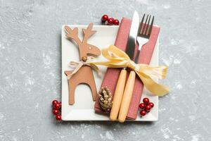 Top view of holiday dinner decorated with dried fruit and cinnamon on cement background. Set of plate, urensil and New Year decorations. Christmas time concept with epmty space for your design photo