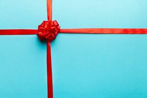 Top view of Red ribbon rolled and red bow isolated on colored background. Flat lay with copy space photo