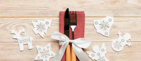 Top view of New Year dinner on wooden background. Festive cutlery on napkin with christmas decorations and toys. Banner family holiday concept with copy space photo
