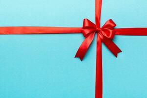 Top view of Red ribbon rolled and red bow isolated on colored background. Flat lay with copy space photo