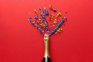 Creative flat lay composition with bottle of champagne and space for text on color background. Champagne bottle with colorful party streamers. holiday or christmas concept photo