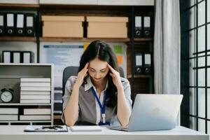 Asian business woman is stressed, bored, and overthinking from working on a tablet at the modern office. photo