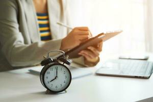 Alarm clock on the desk. Business hand using smartphone, laptop and tablet  working in modern office building photo