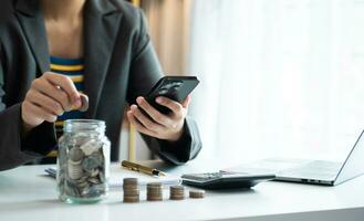 Hand putting mix coins and seed in clear bottle and business investment growth concept. at office photo