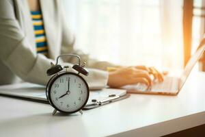 Alarm clock on the desk. Business hand using smartphone, laptop and tablet  working in modern office building photo