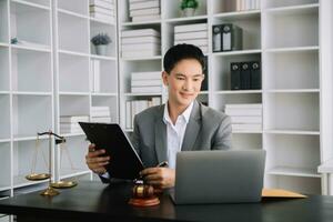 Attractive young lawyer in office Business man and lawyers discussing contract papers laptop and tablet with brass scale on  desk in office. photo