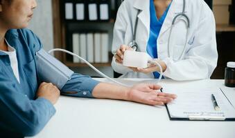 A professional physician talks to discuss results or symptoms and gives a recommendation to a male patient and signs a medical paper at an appointment visit in clinic. photo