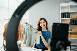 Asian lady blogger showing clothes in front of the camera to recording vlog video live streaming photo