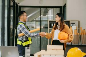 escritorio de ingeniero con papel de objeto y tableta con trabajo en equipo de ingenieros borrosos que trabajan duro para consultar sobre su proyecto de construcción. foto