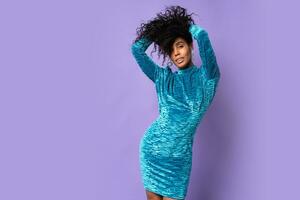 Sexy african american woman with afro hairstyle. Girl wearing white velvet festive dress.  Looking at camera. Studio shot. Blue violet  background. photo