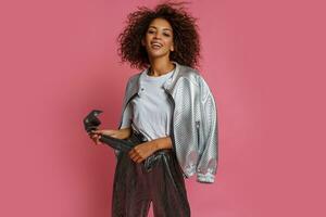 pretty mix race woman with  curly Afro hairs posing on pink background. photo