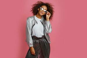 bonito mezcla carrera mujer con Rizado afro pelos posando en rosado antecedentes. foto