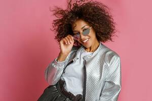 pretty mix race woman with  curly Afro hairs posing on pink background. photo