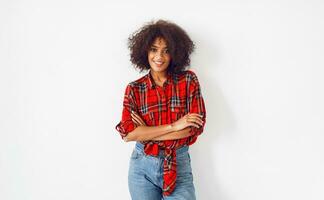 black girl posing over white background. Wearing red checkered shirt. Blue jeans. photo