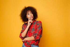 estudio imagen de pensando hermosa joven africano mujer posando aislado terminado naranja antecedentes vestido en rojo camisa. foto