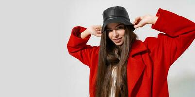 Trendy winter accsesorises. Pretty girl in black hat and red coat  raised hands and holding capi n studio on white background. photo
