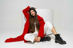 Fashionable  model in stylish  hat, red coat and boots  posing on white background in studio. photo