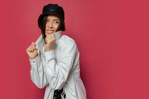 bonito mujer con Perfecto sonrisa vestido en elegante gorra y blanco chaqueta posando en rosado antecedentes. aislar. primavera Moda tendencias foto