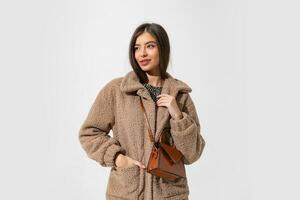 Studio  photo of fascinating woman in winter fur coat posing on white background.