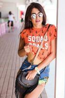 al aire libre estilo de vida retrato de joven increíble morena mujer , naranja impresión camiseta . foto