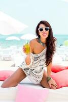 Summer portrait of beautiful brunette woman chilling  in the beach club. Tropical acsessories. photo