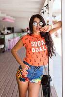 Outdoor   lifestyle  portrait of young amazing brunette woman , orange print t-shirt . photo